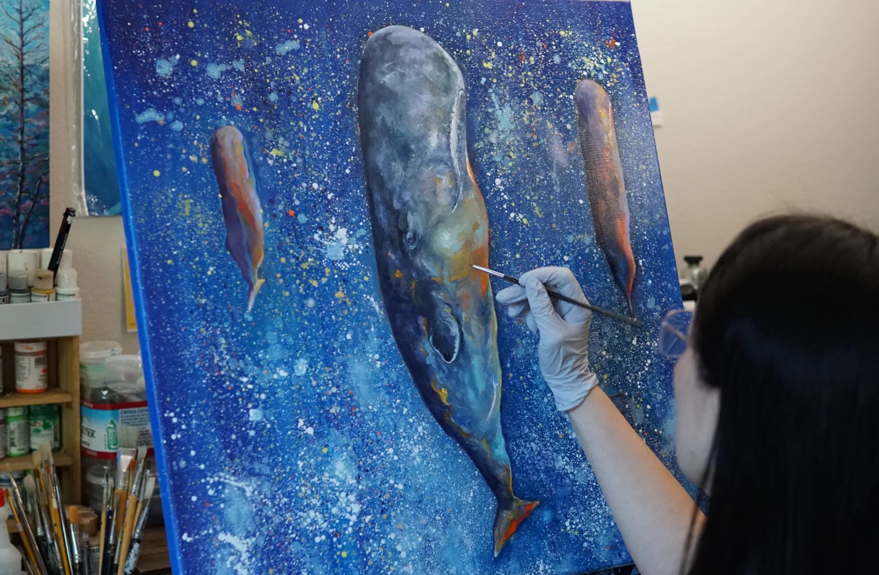 A brush adding detail to the whale painting, seen over Iris’s shoulder.